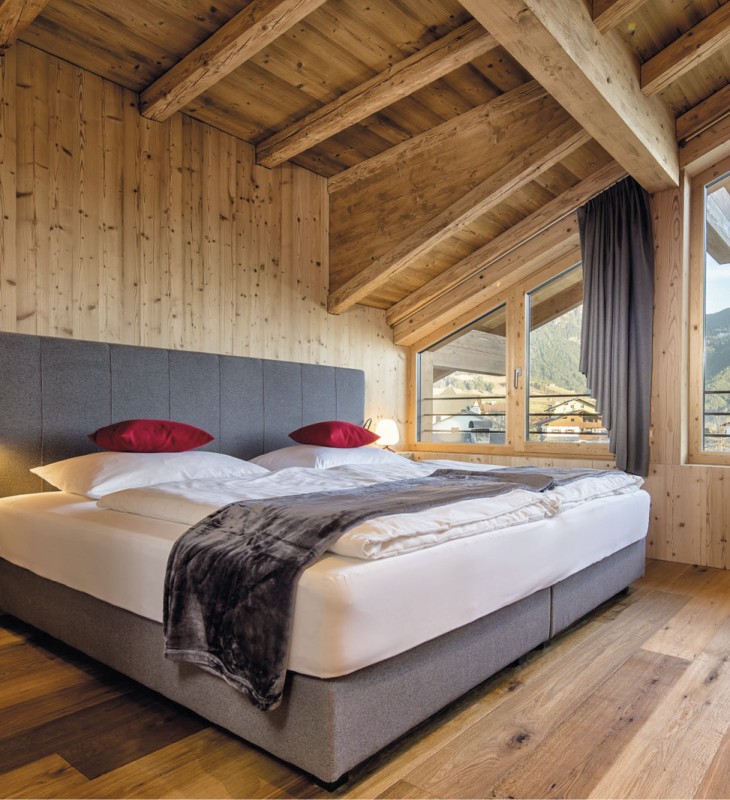 hubertus dolomites Völs am Schlern | Lichtdurchflutete Zimmer: strahlendes Refugium für pure Entspannung Ein Zimmer im Hubertus mit einem Kingsize Bed in Altholz.