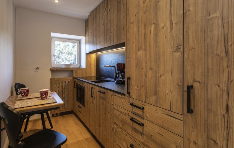 Die Küche der Ferienwohnung. Man sieht eine vollausgestattete Küche mit einem kleinen Esstisch und zwei Stühlen.