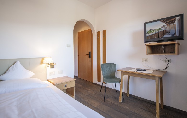 Gemütliches Einzelbettzimmer mit Schreibtisch und Fernseher.