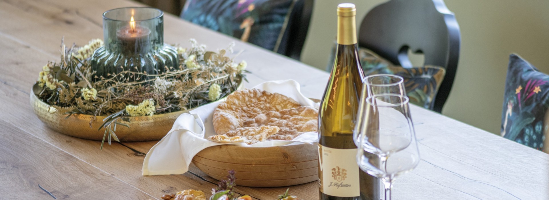 Der Tisch der Gemeinschaftsküche ist stets mit guten Dingen geschmückt, hier mit einer Flasche Wein, typisch hartem Brot und einer Kerzendeko.