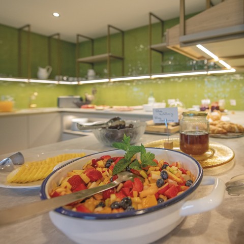 Das Bild zeigt das Frühstücksbuffet. Man sieht Honig, Käse und Obstsalat.