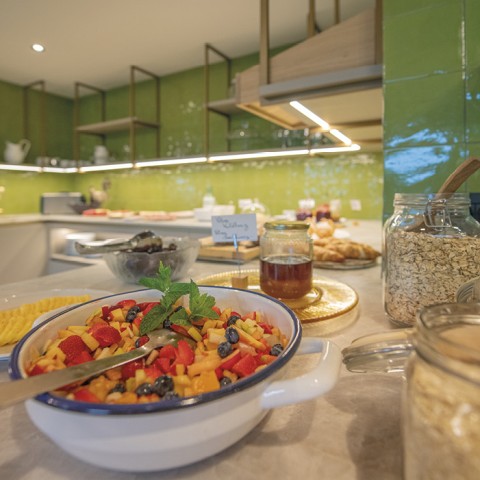 Das Bild zeigt das Frühstücksbuffet. Man sieht Honig, Käse und Obstsalat.