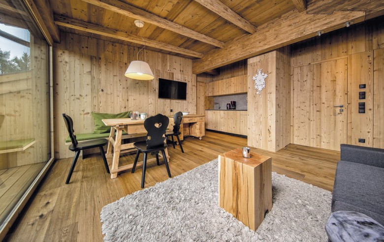 Wohnbereich der Ferienwohnung. Man Sieht einen Holztisch mit schwarzen Stühlen und der Küche im Hintergrund.