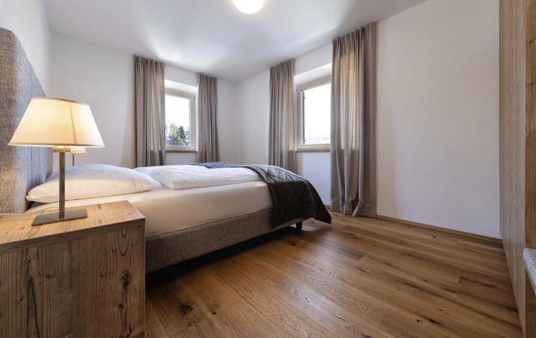 Doppelbett mit zwei Fenstern.