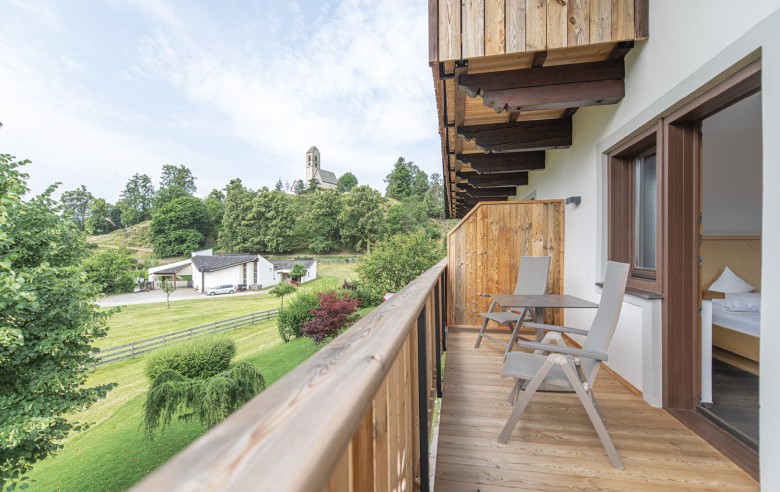 Der Ausblick vom Balkon beschenkt mit der Ruhe der umliegenden Wiesen sowie einer kleinen Kirche.