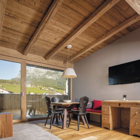 hubertus dolomites Fiè allo Sciliar | Vivere in modo unico ai piedi dello Sciliar Il soggiorno di un appartamento con sedie nere e televisore.