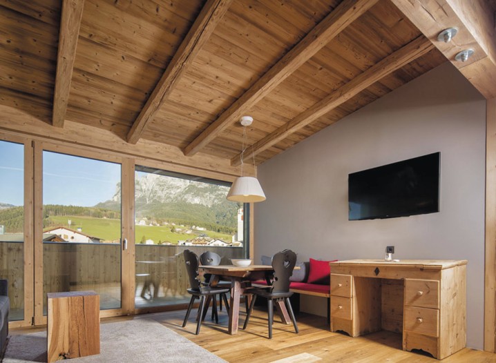 Das Wohnzimmer eines Appartements mit schwarzen Stühlen und einem Fehrnseher.