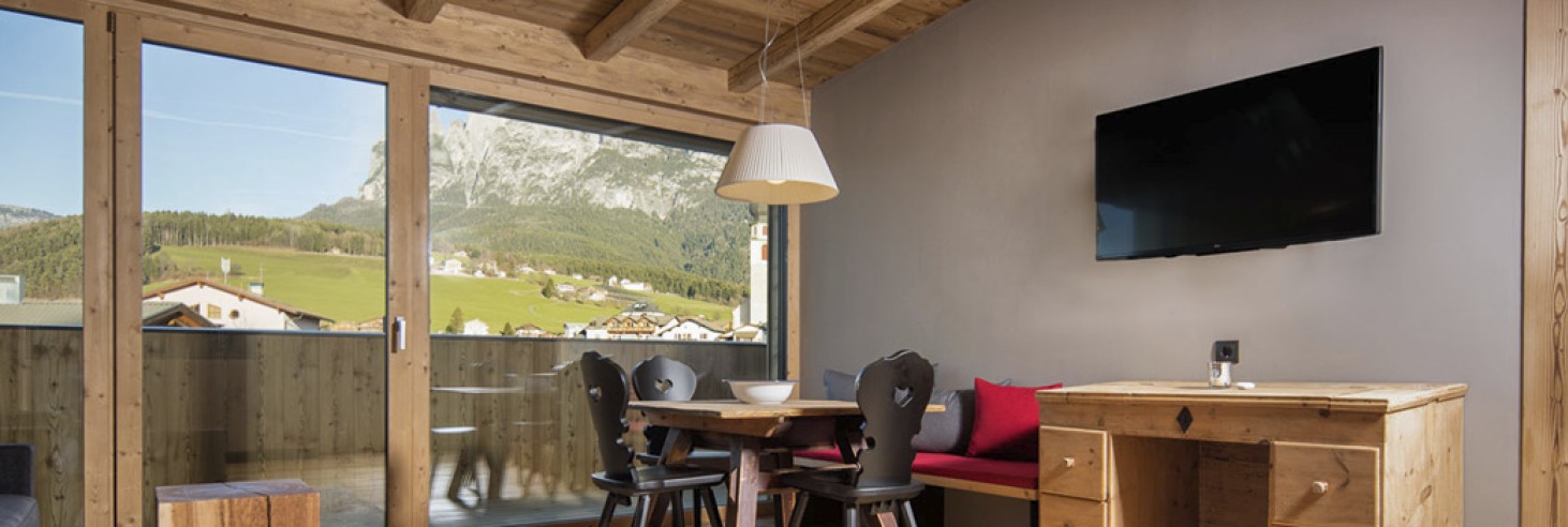 Das Wohnzimmer eines Appartements mit schwarzen Stühlen und einem Fehrnseher.