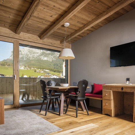 Das Wohnzimmer eines Appartements mit schwarzen Stühlen und einem Fehrnseher.