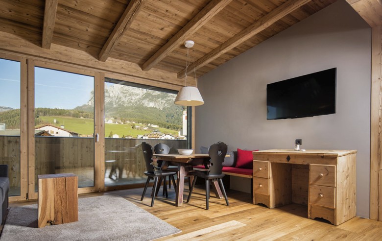 Das Wohnzimmer eines Appartements mit schwarzen Stühlen und einem Fehrnseher.