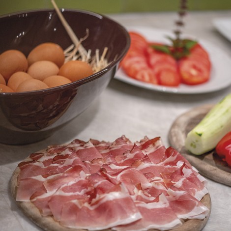 Das Bild zeigt das Frühstücksbuffet. Man sieht frisch gekochte Eier, Speck, Tomaten und Gurken.