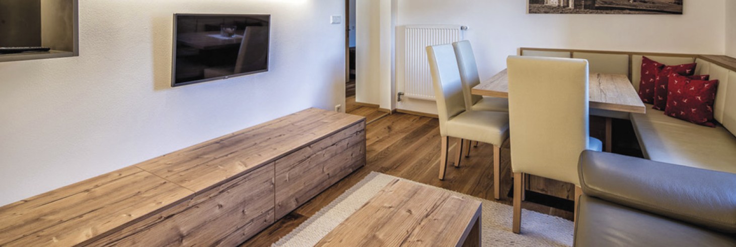 La zona soggiorno con una televisione, un divano e un grande tavolo con sedie.