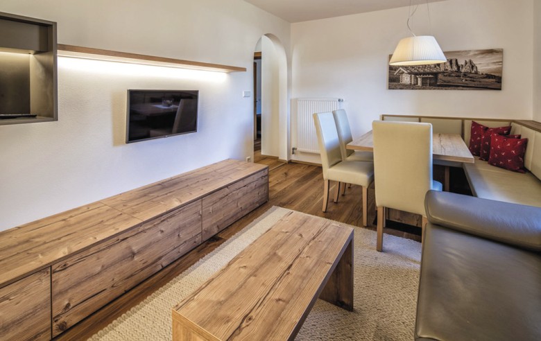 Der Wohnbereich mti einem Fernseher, einer Couch und einen großen Tisch mit Stühlen.