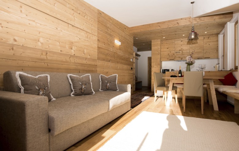 Gemütliches Sofa unter einer duftenden Echtholztäfelung in einem rustikalen und romantischen Chalet für Natururlaub direkt auf der Seiser Alm