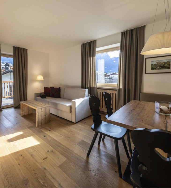 Das helle Wohnzimmer eines Appartements mit Couch und Esstisch.