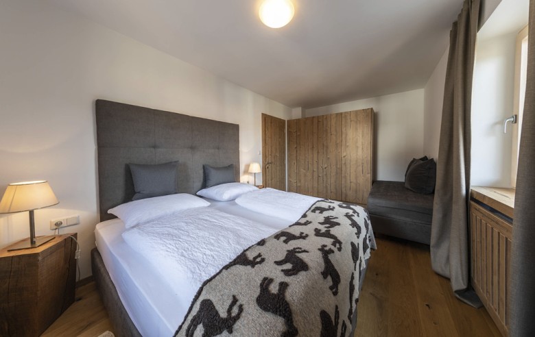 Das Schlafzimmer der Ferienwohnung. Man sieht im Hintergrund den Kleiderschrank sowie eine Sitzecke.