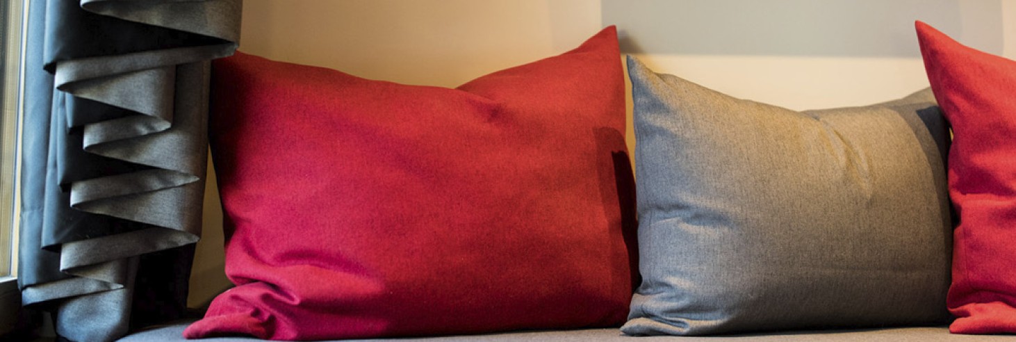 Ein Detailbild der Couch mit roten und grauen Kissen.