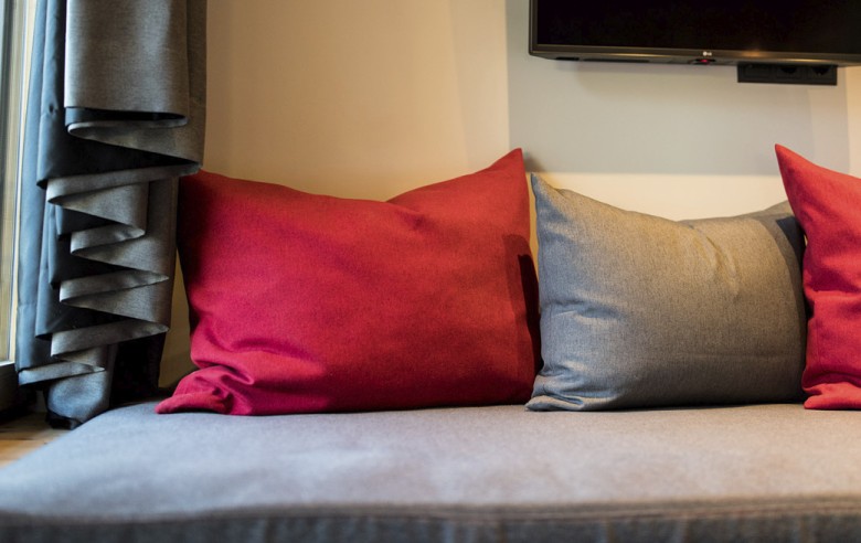 Ein Detailbild der Couch mit roten und grauen Kissen.