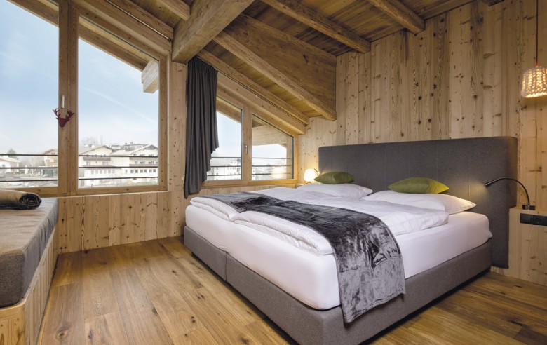 Doppelbettzimmer mit Couch. Es besitzt große Zimmer und ist in Holz gehalten.